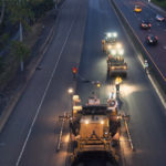 A construction crew applies an asphalt overlay to a highway.